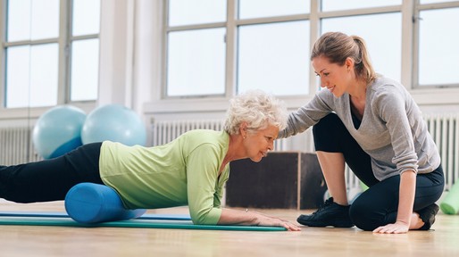 Physical therapist helping elderly woman in her workout