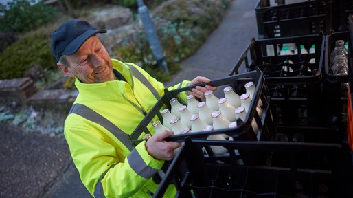 Milkman unloading his milk float in early morning