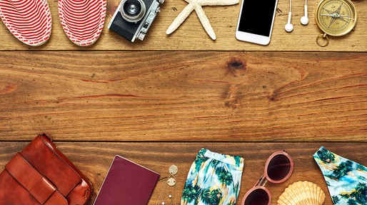 Flat lay of travel and beach accessories on wooden floor