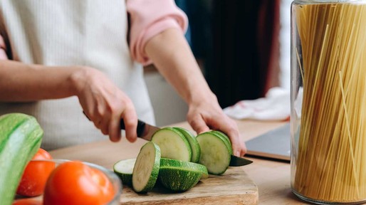 Een vrouw is courgette aan het snijden op een snijplank