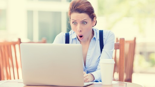 young business woman using laptop looking at computer screen blown away in stupor sitting outside