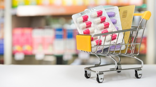 Shopping trolley with medical pills and card with blurred pharmacy shop