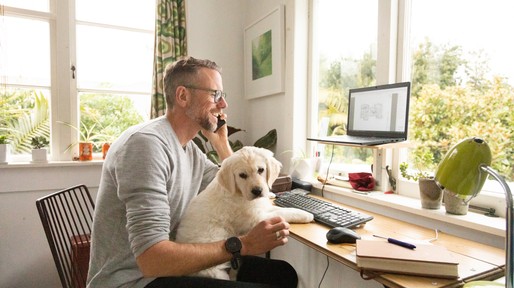 Man working from home with cute puppy on his knee